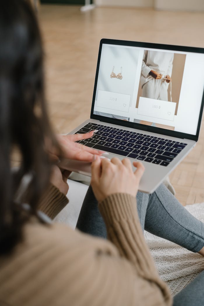 gallery-04 Female browsing an online fashion store on a laptop indoors, focusing on clothing and accessories.