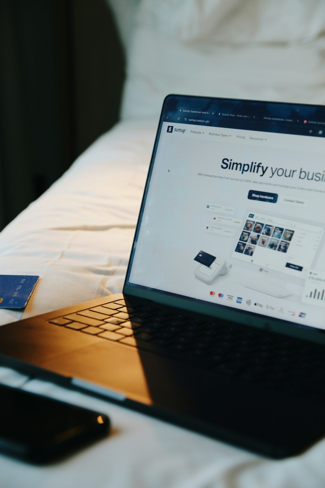 about-img Laptop displaying the SumUp website on a bed, with soft natural light and a credit card nearby. A visual representation of remote business management, online sales, and the flexibility of running a digital-first company from anywhere.
